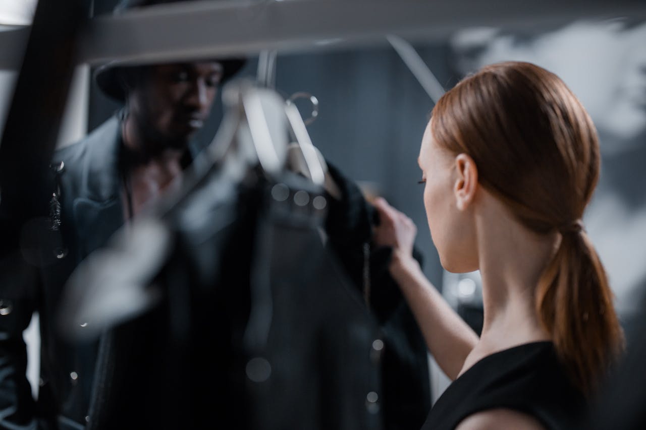 Fashion designer and model preparing for a studio photoshoot with elegant garments.